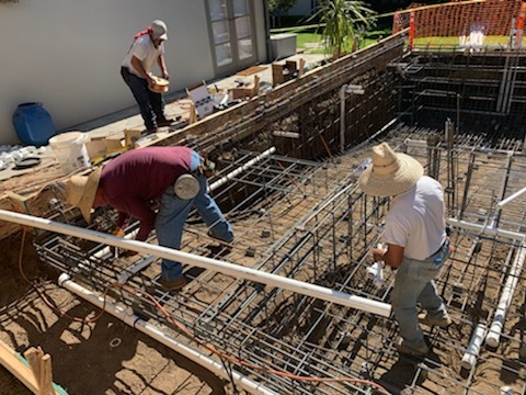 Three people working on building metal pipings.