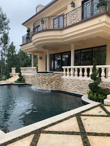 Pool by the side of a two story house.