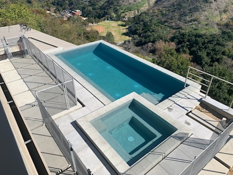 Aerial view of a pool and jacuzzi with a view.