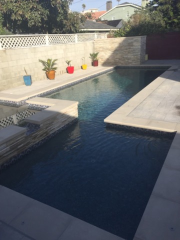 A pool with jacuzzi connected on side.