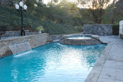 A pool with raised jacuzzi and mini waterfall.