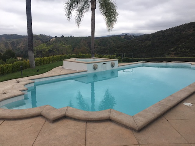 A pool with raised jacuzzi and a view of mountains.