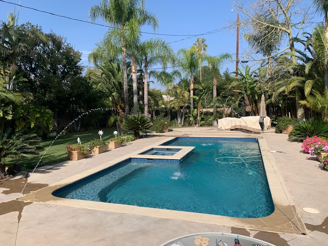 A rectangular pool with a small square jacuzzi in the middle on the side.