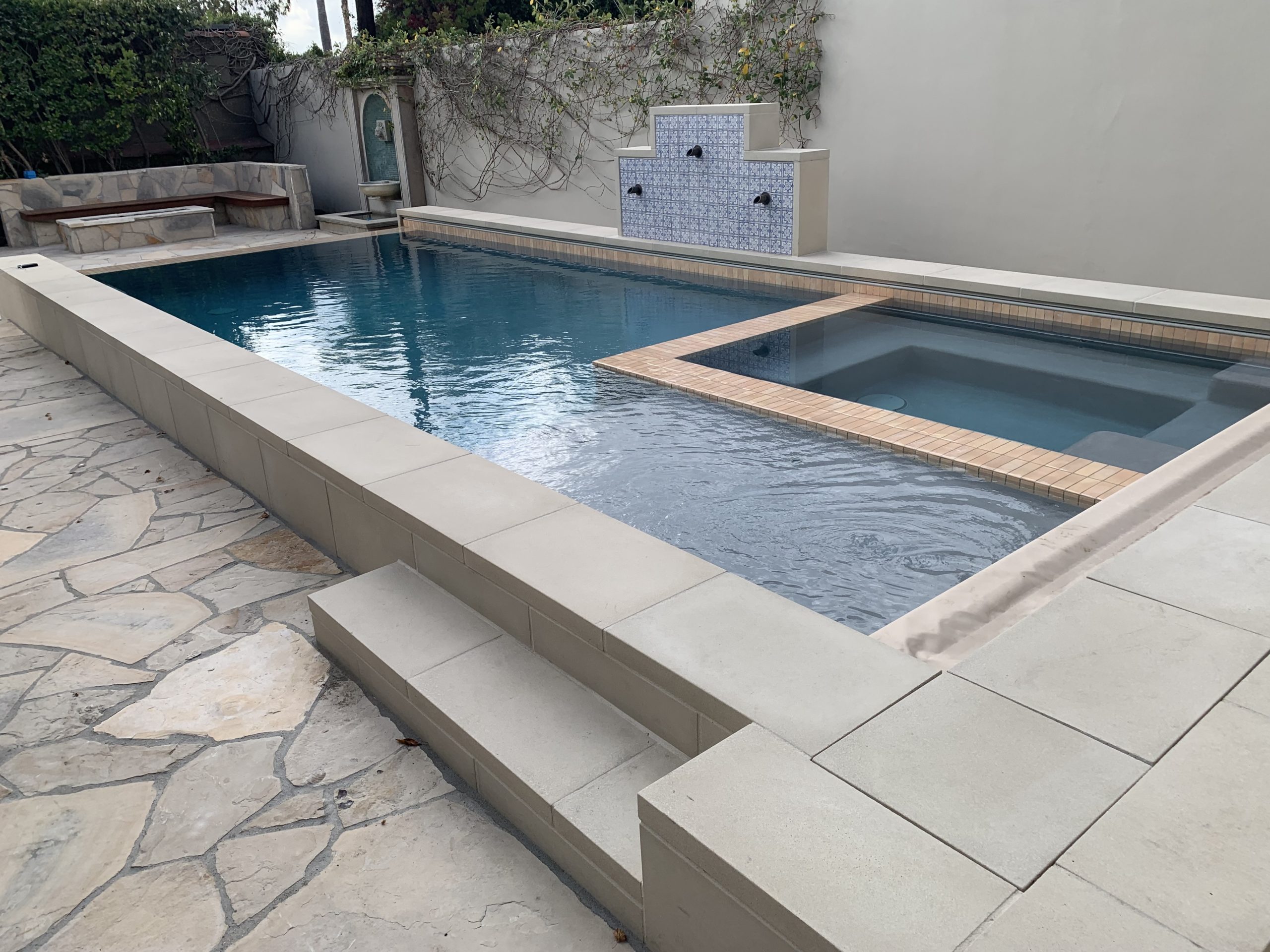 A pool with a jacuzzi in the corner.